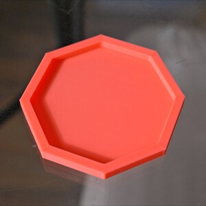 May include: A bright orange hexagonal silicone mold for crafting. The mold has a raised edge around the perimeter.