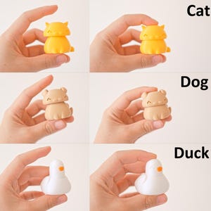 Peut inclure: Trois petites figurines color&eacute;es d'un chat, d'un chien et d'un canard. Le chat est jaune, le chien est brun et le canard est blanc.