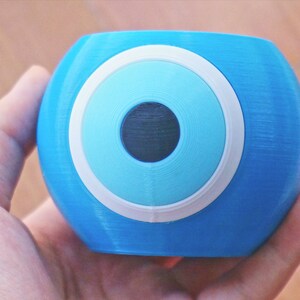 May include: A blue glass paperweight with a white and blue evil eye design.