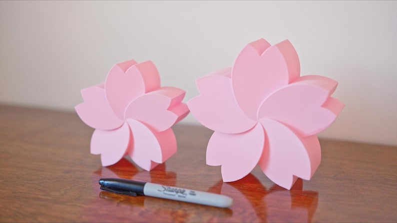May include: Two pink ceramic flower-shaped boxes. The larger box is about 6 inches in diameter and the smaller box is about 4 inches in diameter.