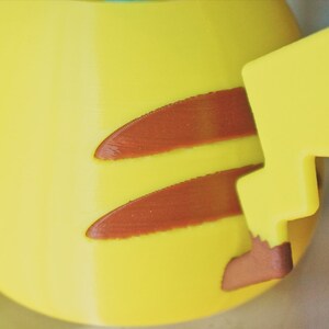 May include: A yellow Pikachu figurine with a brown lightning bolt tail. The figurine is made of plastic and has a smooth surface.