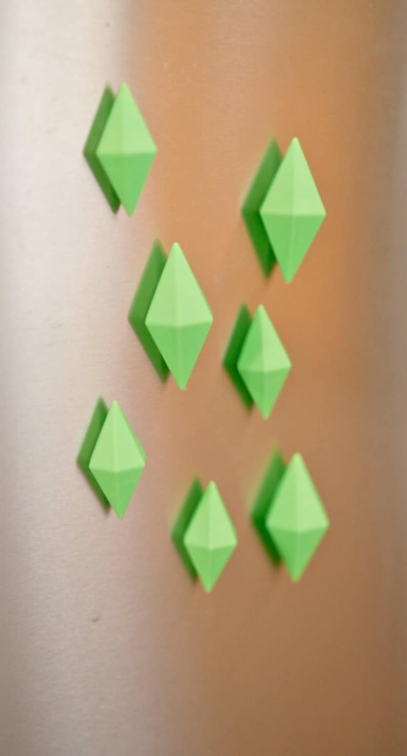 May include: Seven green diamond-shaped magnets on a metallic surface.