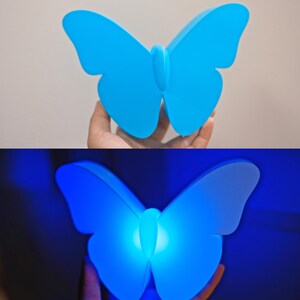 May include: A blue butterfly-shaped night light. The light is a solid, vibrant blue when off, and glows with a bright blue light when illuminated. The wings are curved and detailed, creating a decorative and functional item.
