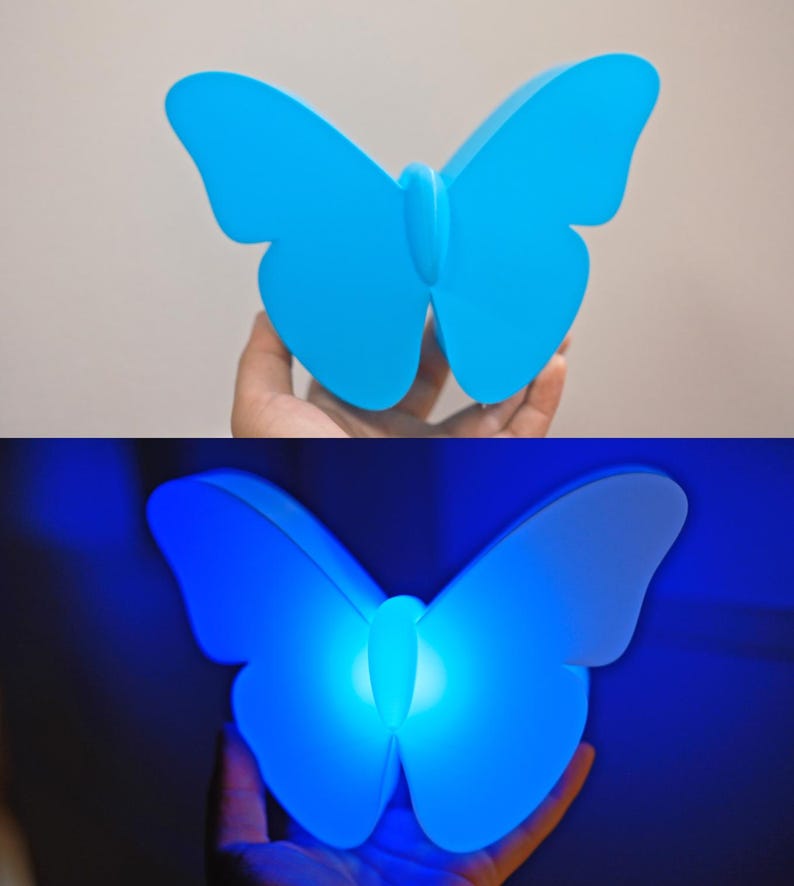May include: A blue butterfly-shaped night light. The light is a solid, vibrant blue when off, and glows with a bright blue light when illuminated. The wings are curved and detailed, creating a decorative and functional item.