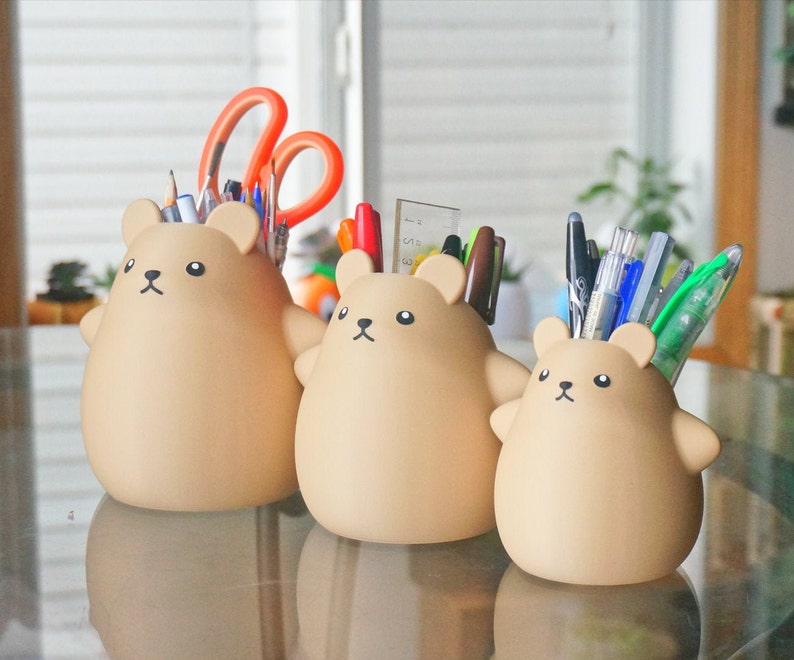 May include: Three brown bear-shaped desk organizers with a variety of pens, pencils, and scissors inside.
