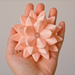 May include: A peach-colored origami flower with a small clear light in the center.