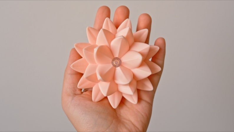 May include: A peach-colored origami flower with a small clear light in the center.