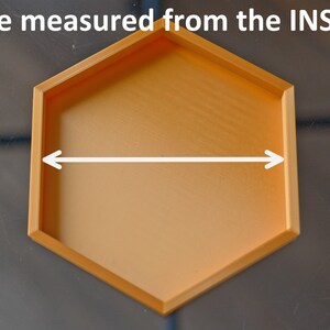 May include: A gold hexagonal tray with a smooth surface. The tray is 6 inches wide, measured from the inside.