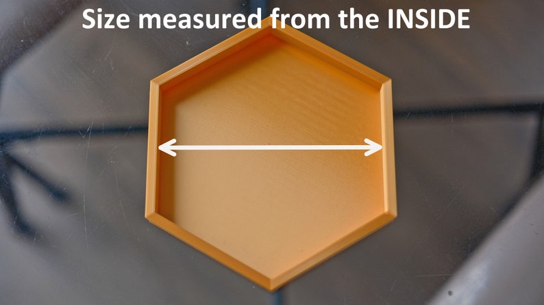 May include: A gold hexagonal tray with a smooth surface. The tray is 6 inches wide, measured from the inside.