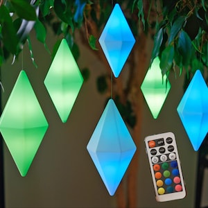 May include: A set of six diamond-shaped LED lights hanging from a tree branch. The lights are in various colors, including blue, green, and purple. A remote control is included to change the colors of the lights.