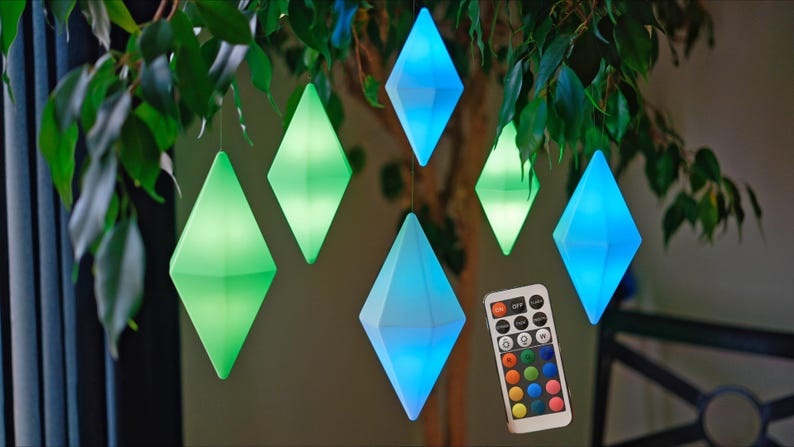 May include: A set of six diamond-shaped LED lights hanging from a tree branch. The lights are in various colors, including blue, green, and purple. A remote control is included to change the colors of the lights.