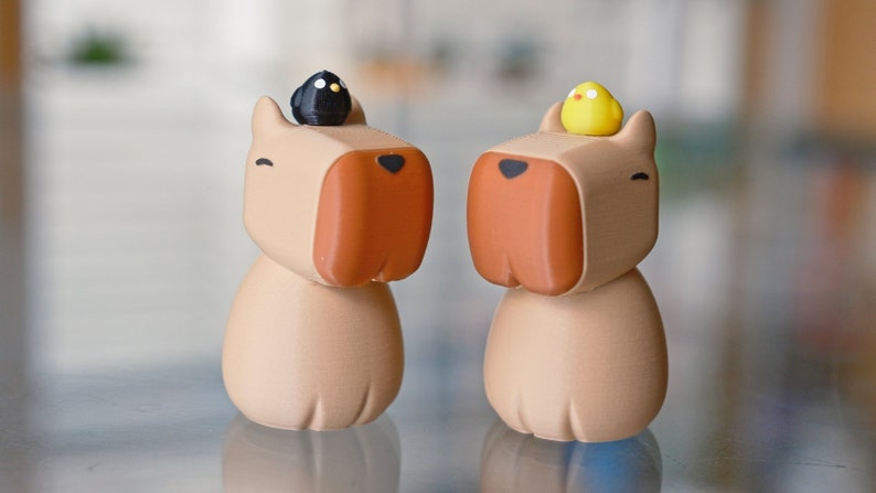 May include: Two brown ceramic figurines of dogs with small bird figurines on their heads. One dog has a black bird and the other has a yellow bird.