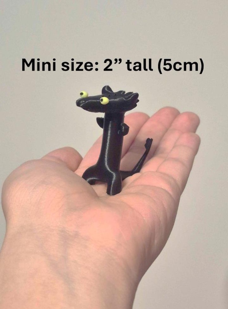 May include: A black, miniature figurine of a creature with yellow eyes, held in a hand. The figurine is 2 inches tall. The text "Mini size: 2" tall (5cm)" is above the figurine.