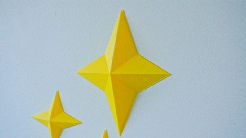 May include: Two yellow paper stars, one large and one small, are attached to a light blue wall.