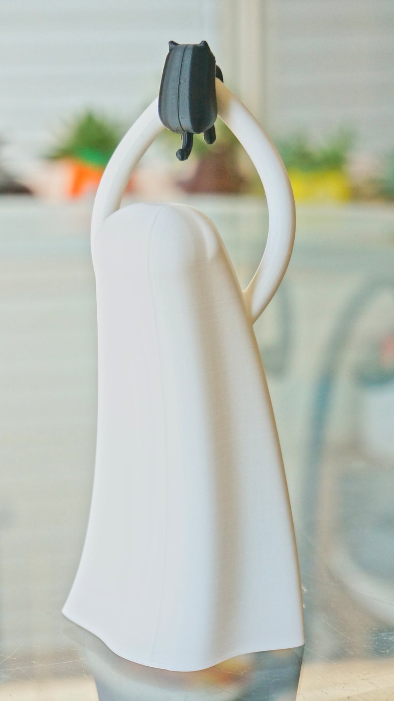 Peut inclure: Un bouchon de bouteille en c&eacute;ramique blanche avec une figurine de chat noir sur le dessus. Le chat est tourn&eacute; dos au spectateur et a une queue recourb&eacute;e.