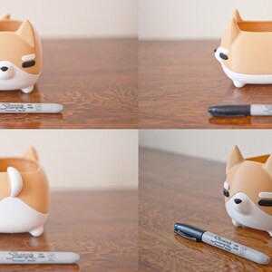 May include: A brown and white ceramic planter shaped like a dog. The planter has a small opening on the top for planting. The planter is sitting on a wooden surface.