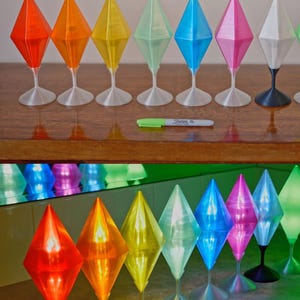 May include: A row of diamond-shaped decorative objects in a range of colours: red, orange, yellow, green, blue, pink, and white. Each sits on a slender stem and base. The text "Clear Color Selection" is above the objects.