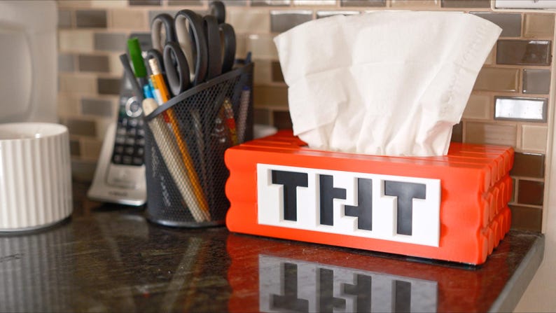 May include: Red tissue box holder with the word "THT" in black letters. The holder is made to look like a stack of red building blocks.