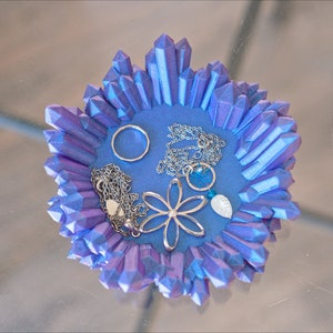 May include: A blue crystal-shaped dish with a silver ring, two necklaces, a silver flower charm, and a blue stone.