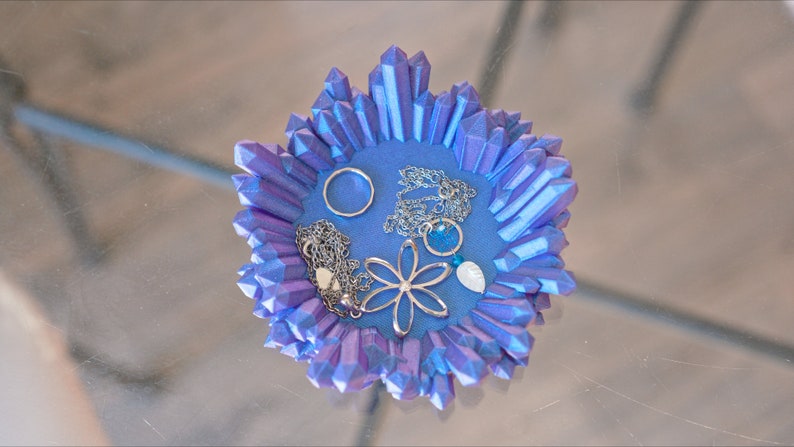 May include: A blue crystal-shaped dish with a silver ring, two necklaces, a silver flower charm, and a blue stone.