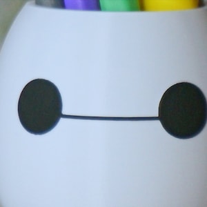 Pu&ograve; includere: Portapenne in ceramica bianca a forma di Baymax del film Disney Big Hero 6. Il portapenne ha occhi neri e una linea nera per la bocca.