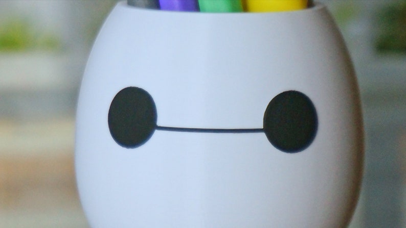 Pu&ograve; includere: Portapenne in ceramica bianca a forma di Baymax del film Disney Big Hero 6. Il portapenne ha occhi neri e una linea nera per la bocca.