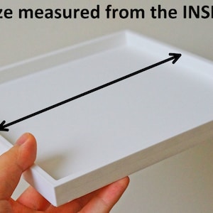 May include: White square tray with a black arrow pointing to the inside of the tray. The text "Size measured from the INSIDE" is above the tray.