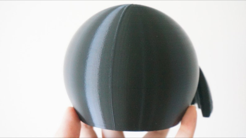 May include: A dark gray sphere with a lighter gray stripe running vertically down the side.