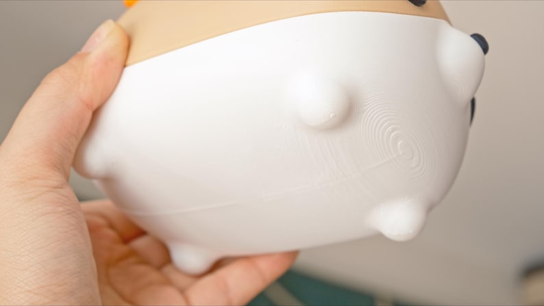 May include: White ceramic planter with a textured bottom and four small feet. The planter has a rounded shape and a smooth, white finish.