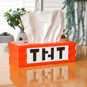 May include: Orange tissue box shaped like a Minecraft block with the word "THT" on the front.