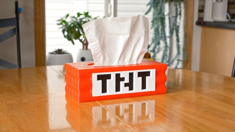 May include: Orange tissue box shaped like a Minecraft block with the word "THT" on the front.