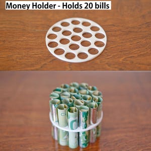 Puede incluir: Un portamonedas blanco con m&uacute;ltiples aberturas circulares, que contiene billetes enrollados. El texto "Money Holder - Holds 20 bills" est&aacute; en la parte superior. El soporte est&aacute; sobre una superficie de madera.