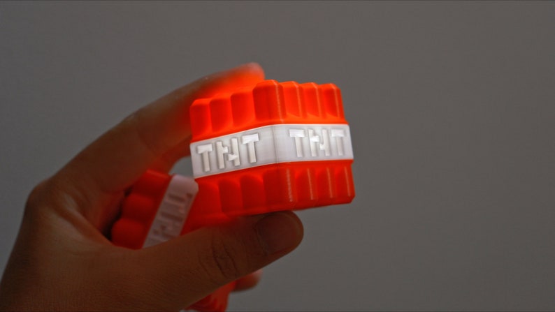 Op de afbeelding: Een rood en wit blok met het woord "THT" gedrukt op elke zijde. Het blok is gemaakt van plastic en heeft een getextureerd oppervlak.