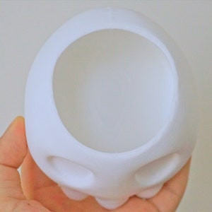 May include: White ceramic skull planter with two eye holes and a large opening at the top for planting.