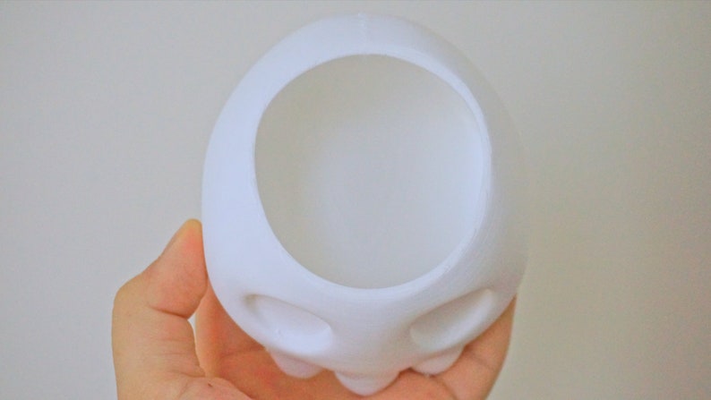 May include: White ceramic skull planter with two eye holes and a large opening at the top for planting.