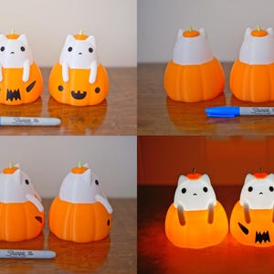 May include: A collection of orange and white cat-shaped Halloween decorations. The cats are sitting inside orange pumpkins with carved faces. A blue marker is placed in front of the decorations.