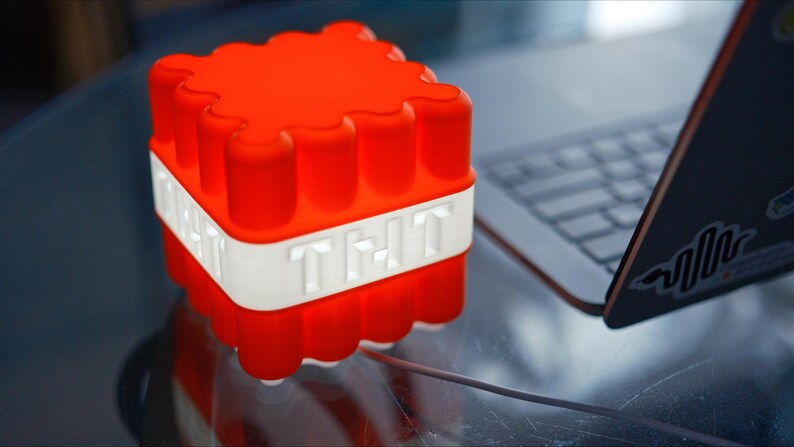 May include: A red and white Minecraft TNT block shaped night light. The light is on and glowing red.