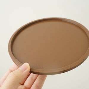 May include: A brown round coaster with a slightly raised edge.