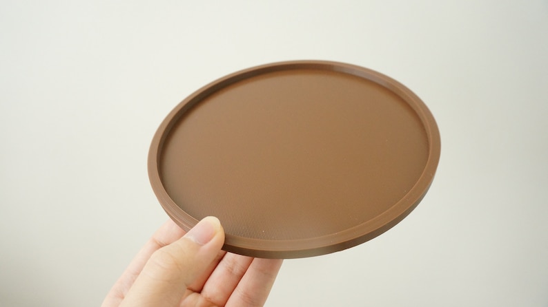 May include: A brown round coaster with a slightly raised edge.