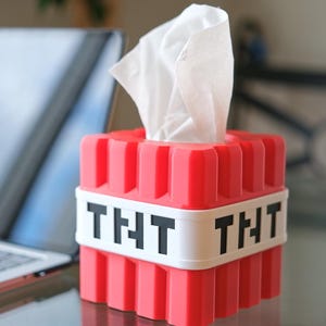 K&ouml;nnte beinhalten: Rote Plastik-Tischbox in Form eines Minecraft TNT-Blocks mit einem wei&szlig;en Etikett, auf dem auf jeder Seite "THT" steht.