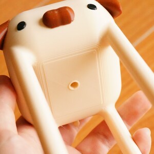 May include: White ceramic planter shaped like a dog with brown ears and a black nose. The planter has a drainage hole in the bottom.