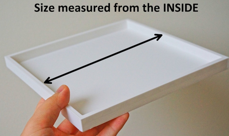 K&ouml;nnte beinhalten: Wei&szlig;es quadratisches Tablett mit einem schwarzen Pfeil, der auf die Innenseite des Tabletts zeigt. Der Text "Size measured from the INSIDE" befindet sich &uuml;ber dem Tablett.
