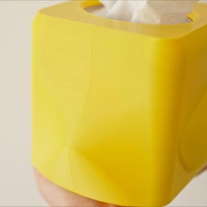 Pu&ograve; includere: Un porta fazzoletti quadrato di colore giallo brillante. La scatola &egrave; realizzata in plastica e ha una finitura liscia e lucida.