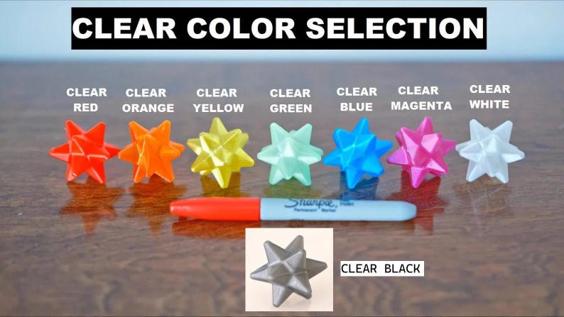 May include: A selection of eight clear plastic star-shaped objects in various colors, including red, orange, yellow, green, blue, magenta, white, and black. The text "CLEAR COLOR SELECTION" is at the top of the image.