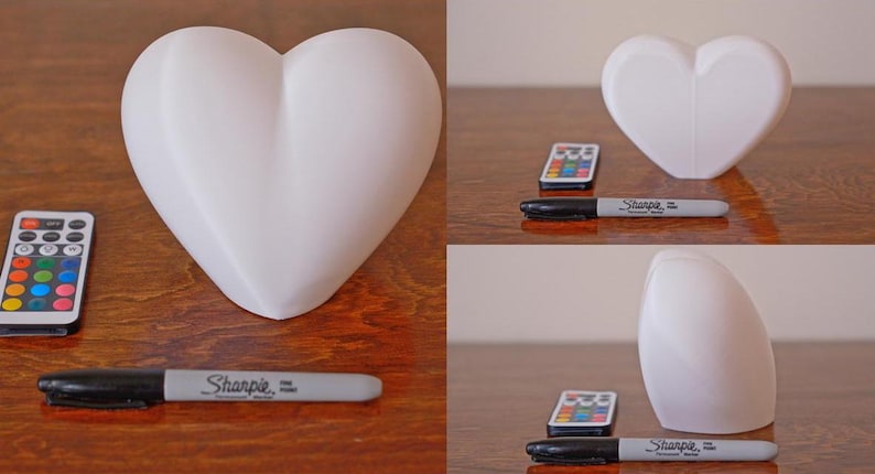 May include: Three white heart-shaped lamps with a remote control and a black Sharpie marker. The lamps are made of a smooth, white material and have a soft, rounded shape.