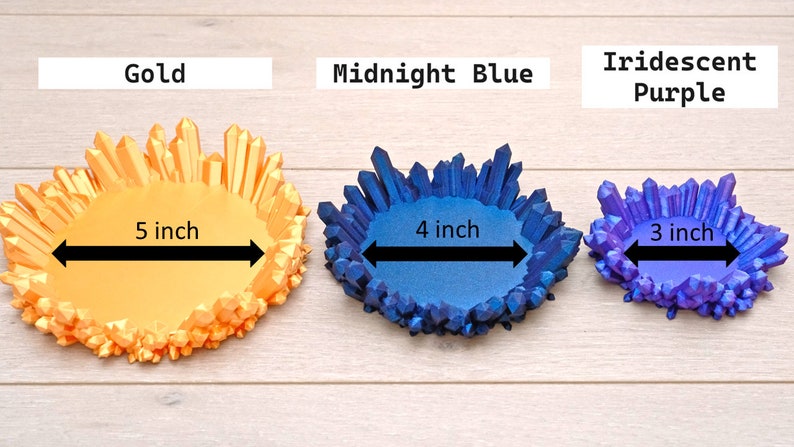 May include: Three crystal dish trays in different sizes and colours. The largest tray is 5 inches wide and gold, the middle tray is 4 inches wide and midnight blue, and the smallest tray is 3 inches wide and iridescent purple.