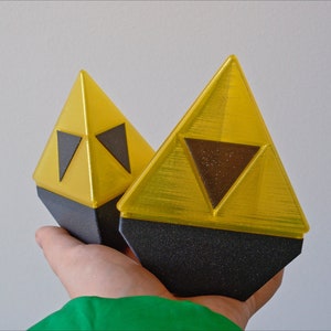 May include: Two yellow triangular-shaped objects with black triangular designs on the front. The objects are made of plastic and have a shiny finish.
