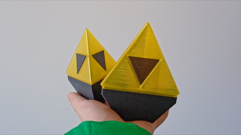 May include: Two yellow triangular-shaped objects with black triangular designs on the front. The objects are made of plastic and have a shiny finish.