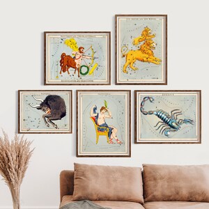 May include: Five framed vintage illustrations of constellations, each depicting a different zodiac sign. The signs are Sagittarius, Leo, Taurus, Gemini, and Scorpio. The illustrations are in a light blue and white color scheme with gold accents.