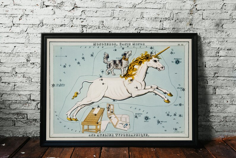 K&ouml;nnte beinhalten: Eine Vintage-Illustration des Sternbilds Monoceros, auch bekannt als das Einhorn, mit einem kleinen Hundesternbild, Canis Minor, dar&uuml;ber. Die Sternbilder sind als ein wei&szlig;es Einhorn mit goldener M&auml;hne und einem schwarz-wei&szlig;en Hund dargestellt. Die Illustration befindet sich auf einem blauen Hintergrund mit Sternen und Text in Schwarzwei&szlig;.